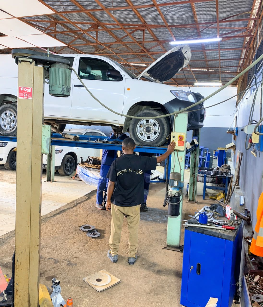 Atelier NK Auto Services à Akwa : un pick-up sur le pont élévateur, techniciens au travail